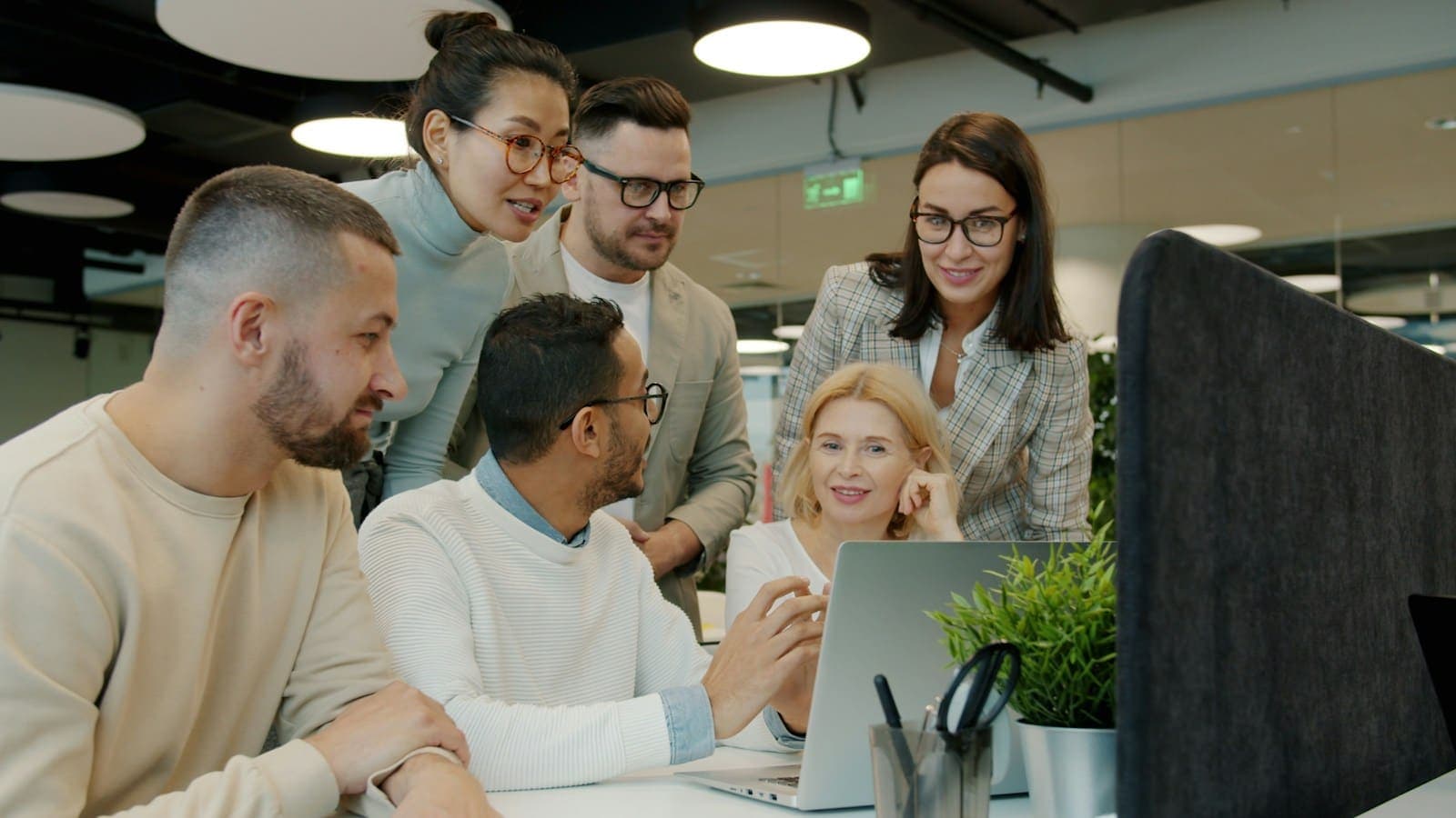 A diverse team gathered around a laptop in a modern office